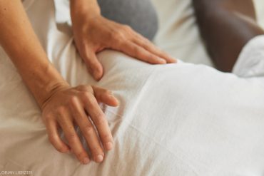 Auf dem Bild sieht man eine Schiatsu Masssaga, Hände am Bauch und so.